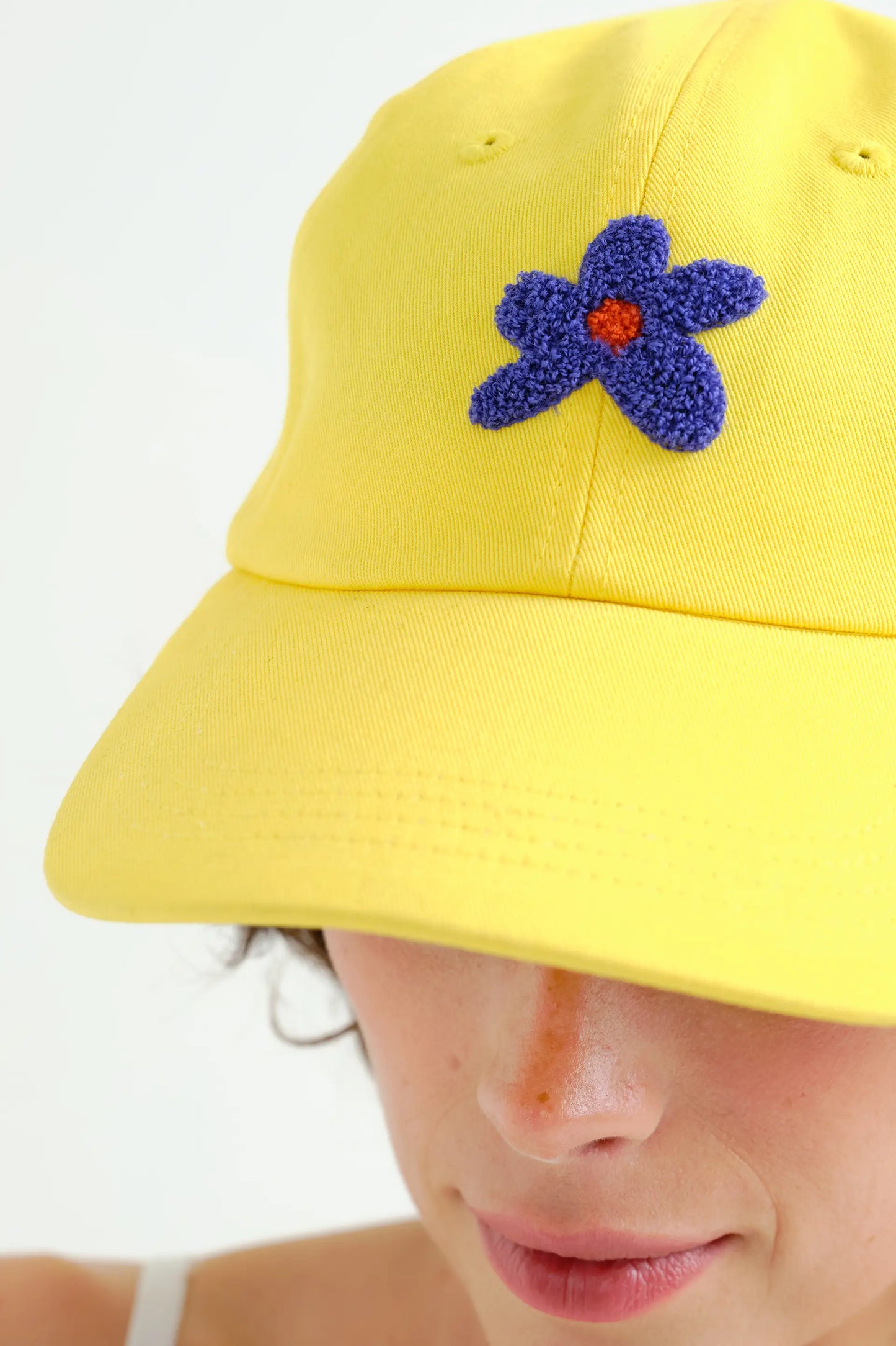 Gorra amarilla con bordado de flor azul